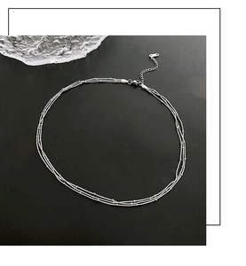 Détail d'un collier argenté à trois rangées avec accents de perles et fermoir mousqueton