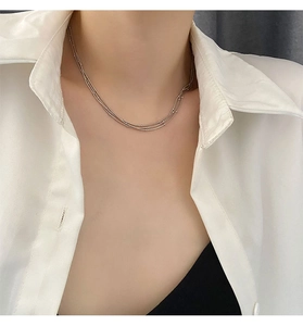 Gros plan d'un collier argenté à trois couches avec petites perles sur un modèle