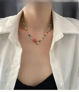 Close-up of colorful beaded necklace with red bead and golden heart pendant