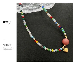 Close-up of colorful beaded necklace featuring a gold heart pendant and pink stone bead