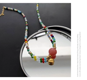 Close-up of colorful beaded necklace with pink crystal bead and gold heart pendant