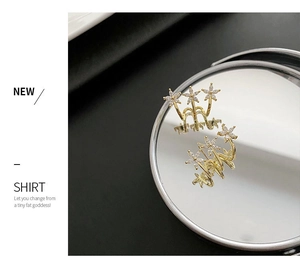 Detail of three-flower gold earrings with zircon inlays on a reflective surface