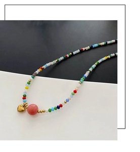 Detail of colorful beads with pink center bead and small golden heart charm pendant