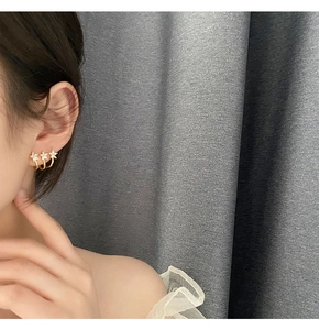 Detailed close-up of a model wearing gold floral ear studs with three white flowers