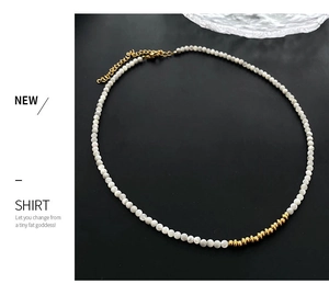 Detail of beaded necklace with white round beads and irregular golden textured accents