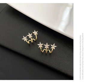 Close-up of gold-plated three-flower ear cuffs with white marquise-cut zircon stones
