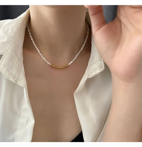 Close-up of a minimalist beaded necklace with white pearls and gold bead accents