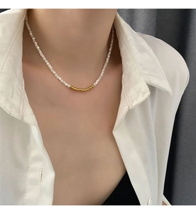 Close-up of elegant small white beads and golden circle detail necklace on a model