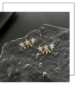 Detailed macro of gold curved earrings with three floral patterns and clear zircons