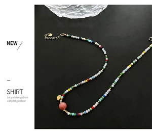Detail of colorful beaded necklace with pink stone bead and golden heart charm