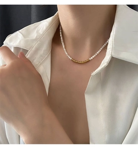 Detail of minimalist pearl choker with gold bead accents on a model's neck