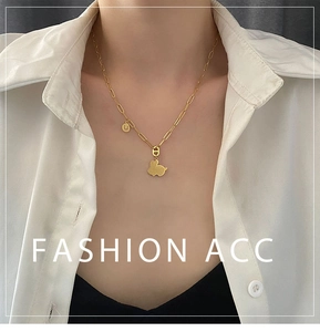 Dettaglio del ciondolo a coniglio dorato e lettera U su una collana a maglia trendy