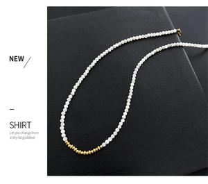 Detail of beaded necklace featuring white pearls and golden metallic spacer accents