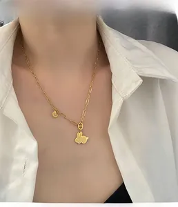 Dettaglio della collana dorata con ciondolo a coniglio e lettera U su catena a graffetta