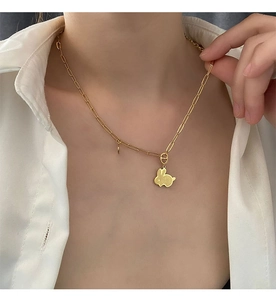 Dettaglio di un ciondolo a coniglio dorato con trama a griglia su una catena a graffetta