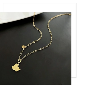 Dettaglio macro del ciondolo a coniglio in oro con maglia H e catena a maglie ovali