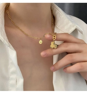 Collana dorata con ciondolo a coniglio e disco con lettera 'u' indossata da una modella