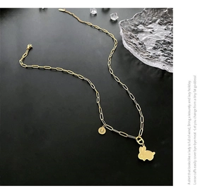 Dettaglio della collana dorata a graffetta con ciondolo a coniglio e charm lettera U