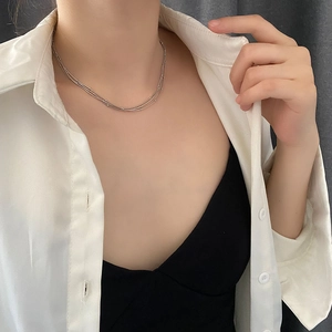 Collier multicouche argenté minimaliste avec détails de perles fines sur un modèle en tenue chic
