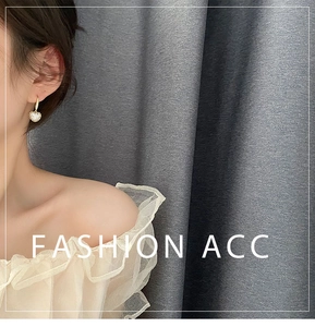 Détail de boucles d'oreilles cœur dorées avec cristaux portées par un mannequin