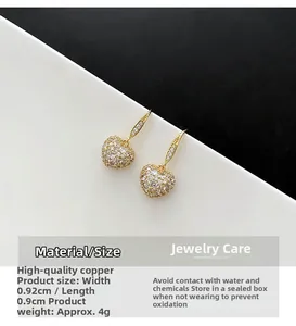 Vue détaillée des boucles d'oreilles cœur dorées avec zircons et base en cuivre poli