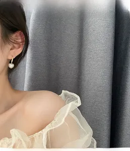 Gros plan de boucles d'oreilles cœur dorées serties de zircons portées par un mannequin