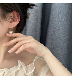 Gros plan de boucles d'oreilles cœur en or serties de cristaux sur un mannequin