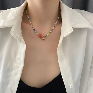 Colorful beaded heart necklace with a pink bead and gold pendant on a model
