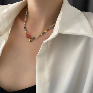 Colorful beaded heart necklace with gold accents and pink bead on model