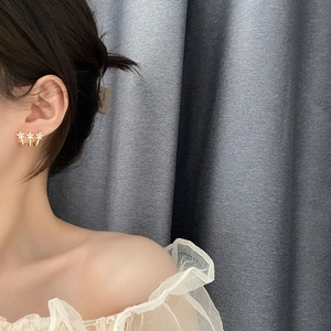 Elegant three-flower gold earrings with white crystals worn by a model in a sweet Korean style