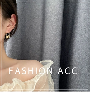 Close-up of elegant gold dangle earrings with cylindrical pendants on a model's ear