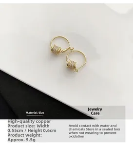Detailed macro view of gold hoop earrings with white zircon cylinder drop pendants