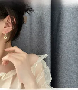 Detailed view of model wearing gold zircon earrings with elegant circular pendants
