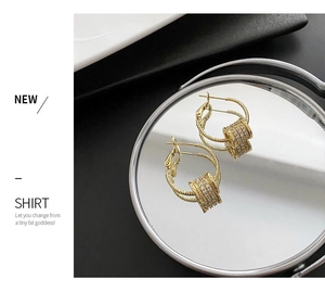 Detailed close-up of golden spiral earrings with micro-set white zircon cylinder
