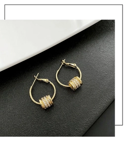 Close-up of gold hoop earrings with zircon-encrusted cylindrical sliders and luxury finish