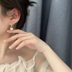 Élégantes boucles d'oreilles cœur en or serties de cristaux portées par un mannequin chic
