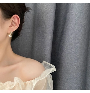 Close-up of elegant gold hoop earrings with heart pearl charms worn by a model