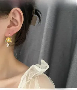 Detailed close-up of sunflower zircon drop earring worn on model for luxury fashion look