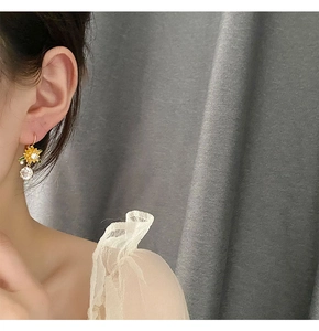 Detail view of sunflower crystal earrings with a large drop gemstone on a model's ear