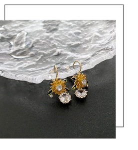 Macro detail of sunflower drop earrings with yellow petals and sparkling crystals