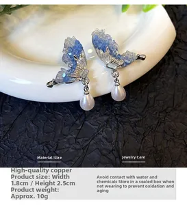 Detailed shot of blue crystal butterfly wing earrings with white pearl drop on copper