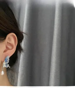 Detailed view of fairy butterfly wing earrings with blue crystals and a drop pearl