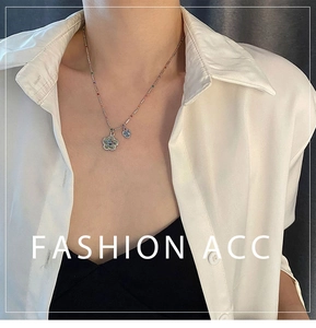 Gros plan du collier argenté avec pendentif fleur sourire coloré et cœur bleu sur modèle