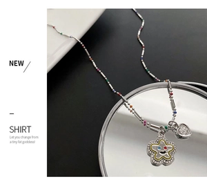 Détail d'une chaîne perlée colorée avec pendentif fleur étoile et breloque coeur