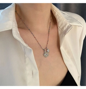 Détail d'un collier de perles colorées avec pendentif fleur sourire et breloque coeur argent