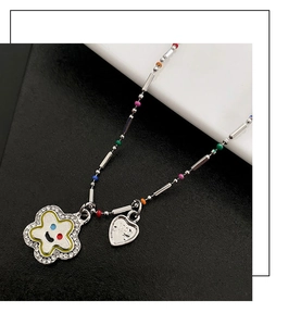 Détail d'un collier de perles colorées avec pendentif fleur en zircon et visage souriant