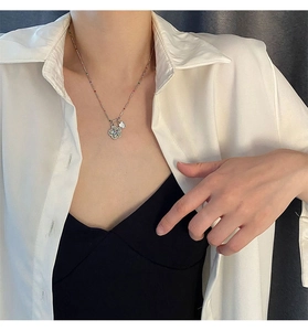 Gros plan d'un collier de perles avec pendentifs fleur et cœur porté par un mannequin