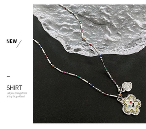 Détail macro d'un collier de perles colorées avec un pendentif fleur souriante serti de cristaux
