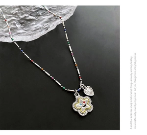 Détail d'un collier de perles colorées avec fleur sourire en zircon et pendentif cœur
