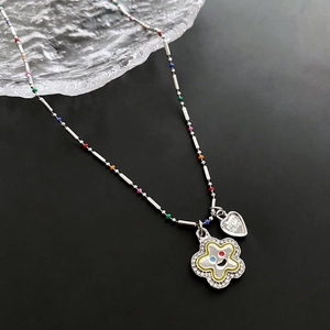 Collier argenté avec pendentif sourire en zircon et cœur sur un plateau en verre texturé